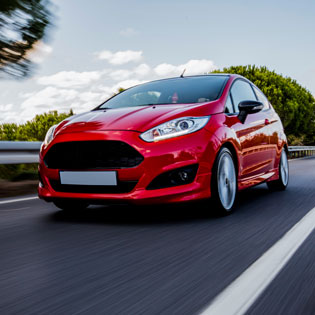 voiture d'occasion rouge roule sur une route