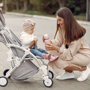 mère avec son bébé lui donnant à boire dans une poussette