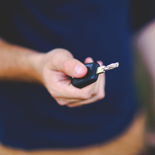 personne tenant une clé de voiture dans la main