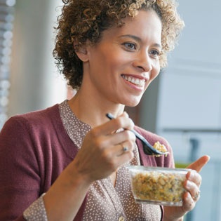 femme souriante déjeunant à son bureau