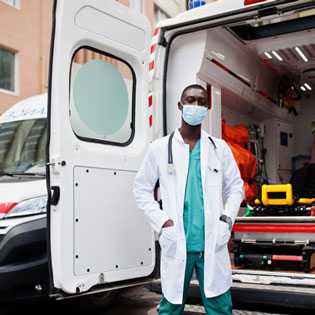 ambulancier masqué devant une ambulance porte ouverte