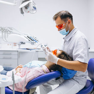dentiste en train d'ausculter la bouche d'une patiente