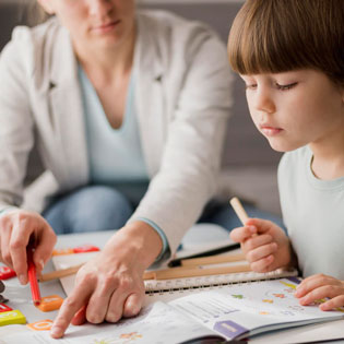 professeure donnant des cours de soutien scolaire à un petit garçon