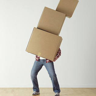 homme portant avec difficulté des cartons de déménagements