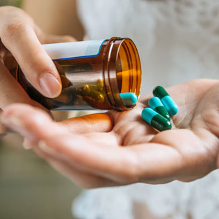 person pouring capsules into his hand