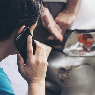 expert en assurance devant un véhicule endommagé