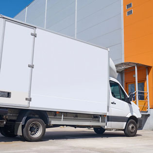 camion utilitaire blanc devant un centre logistique