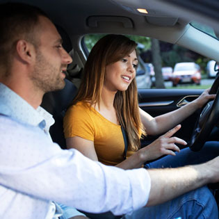 professeur d''auto-école montre un bouton à une jeune conductrice