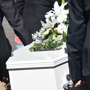 hommes portant un cercueil blanc et fleuri