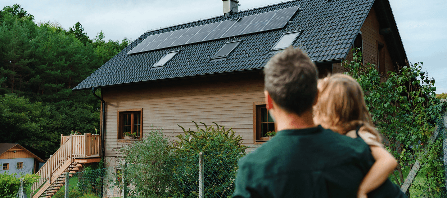 A home fitted with solar panels, viewed by a family - illustrating the insurance sector