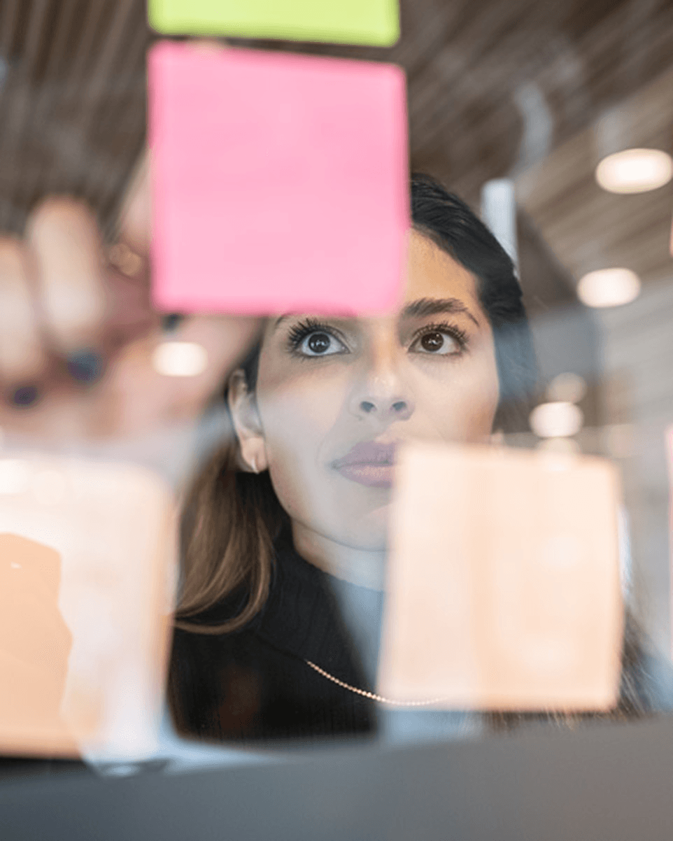 Brainstorming session on a glass wall with sticky notes, focused on consumer product development e produits de consommation