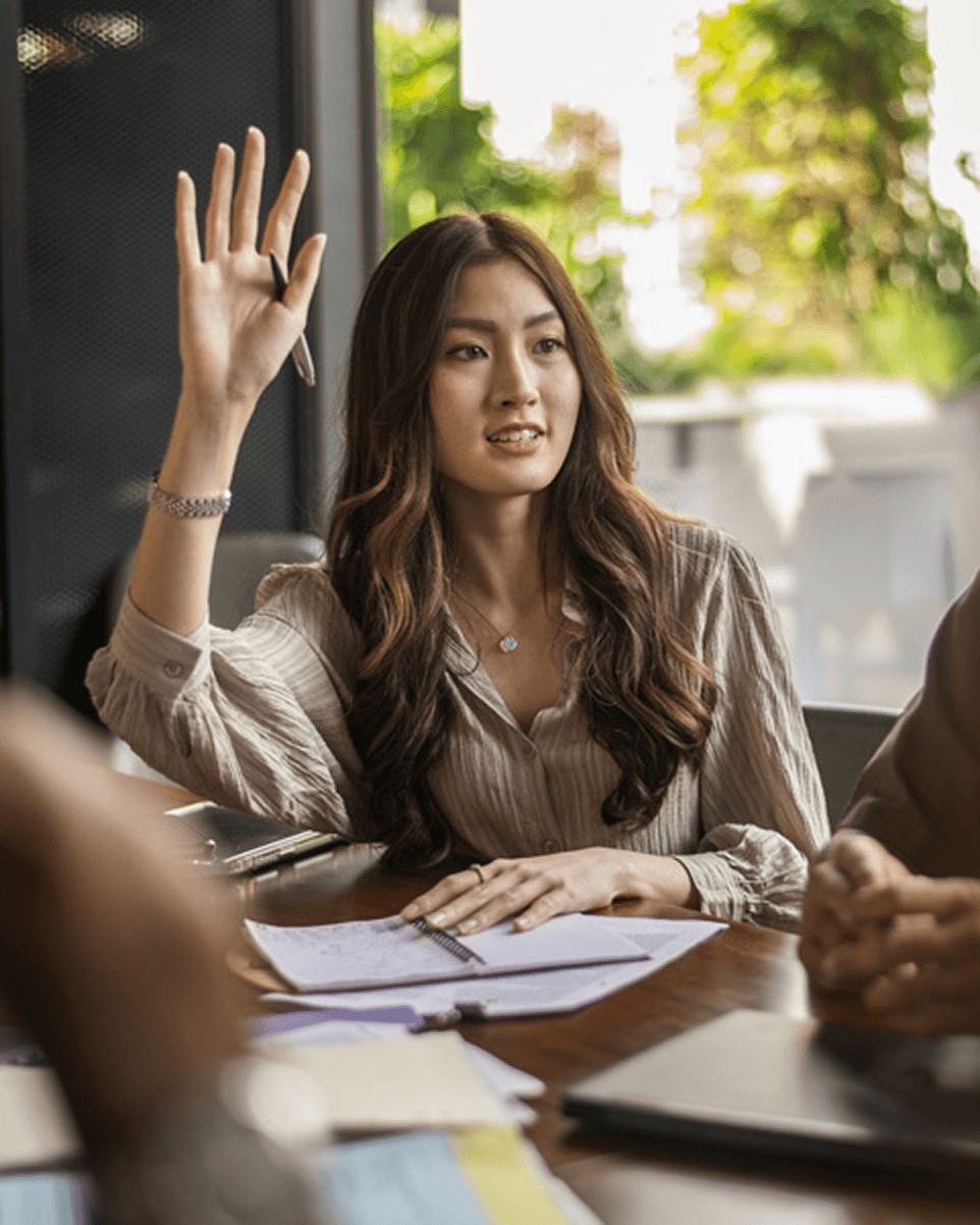 A female colleague raising her hand to speak during a meeting